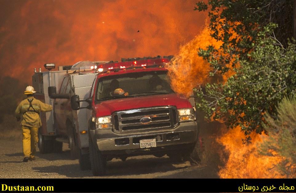 The fire is seen surrounding a fire department vehicle in Santa Calrita, California. Thousands of homes have already been evacuated 