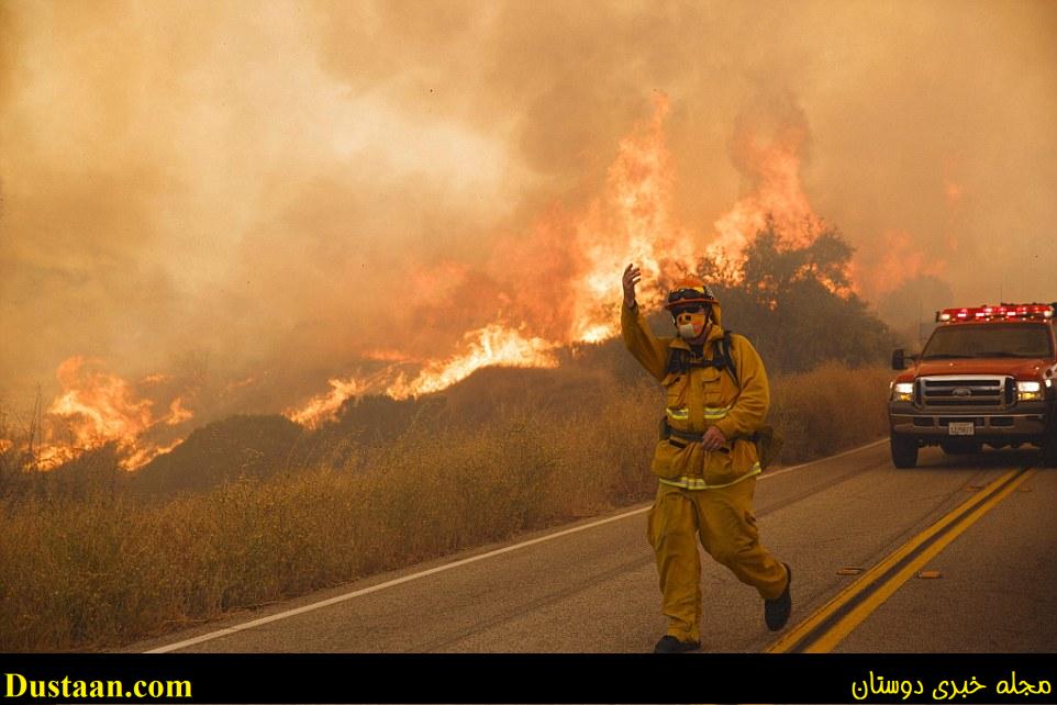 A firefighter wearing a gas mask summons his colleagues as they battle the raging fire in Santa Clarita 
