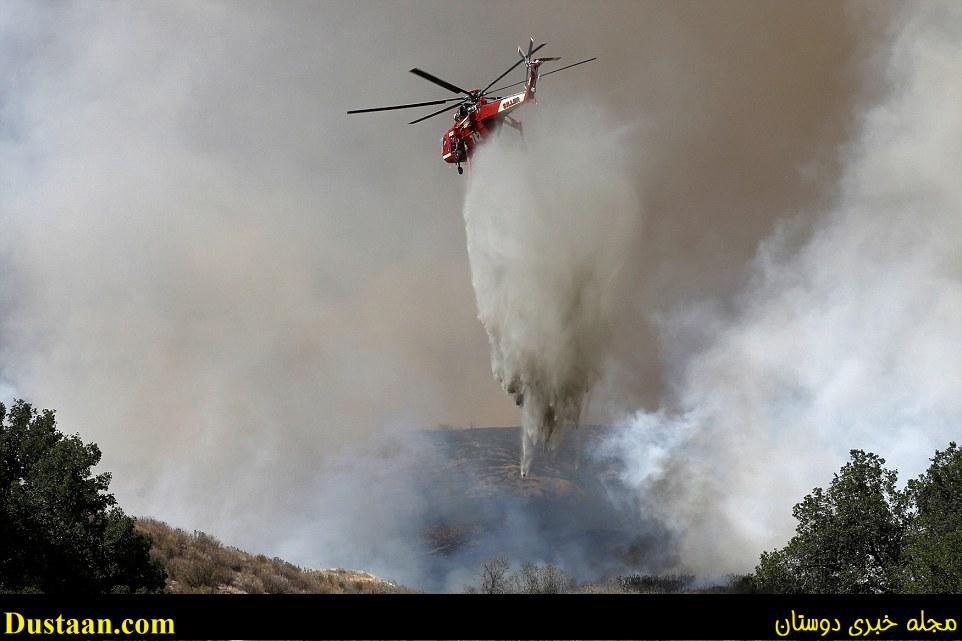 A helicopter drops flame retardant onto the land below. Planes brought in to fight the fire had to be grounded because of the smoke 