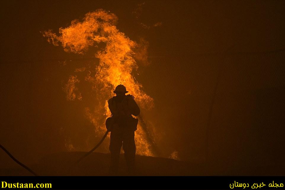 A firefighter hoses down burning pipes near a water tank at the Sand Fire on Saturday near Santa Clarita, California
