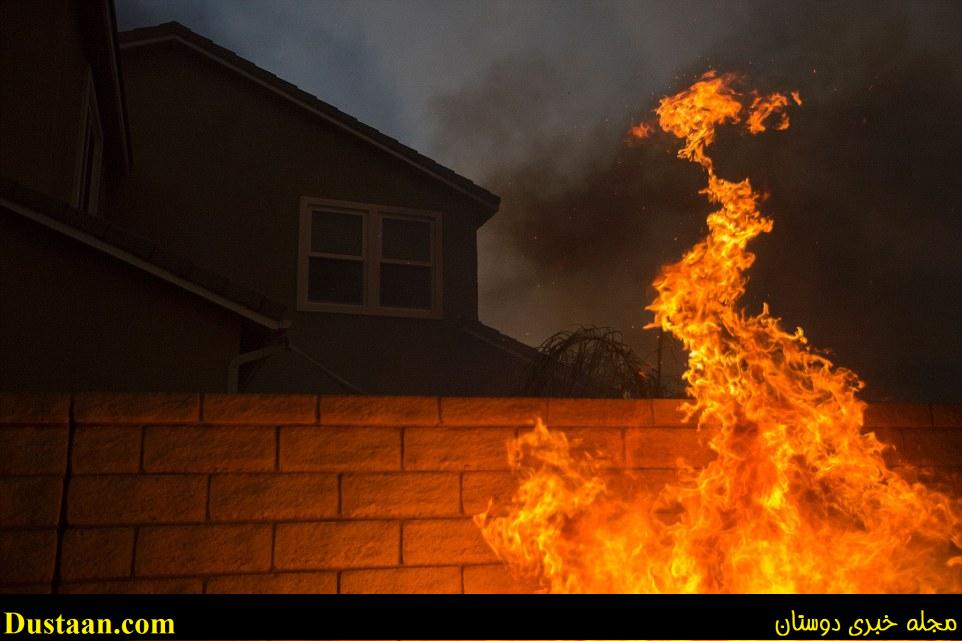 The blaze in northern Los Angeles County grew to more than 35 square miles, spreading smoke across the city and suburbs, reducing the sun to an orange disk at times. Above flames lap a wall of a home