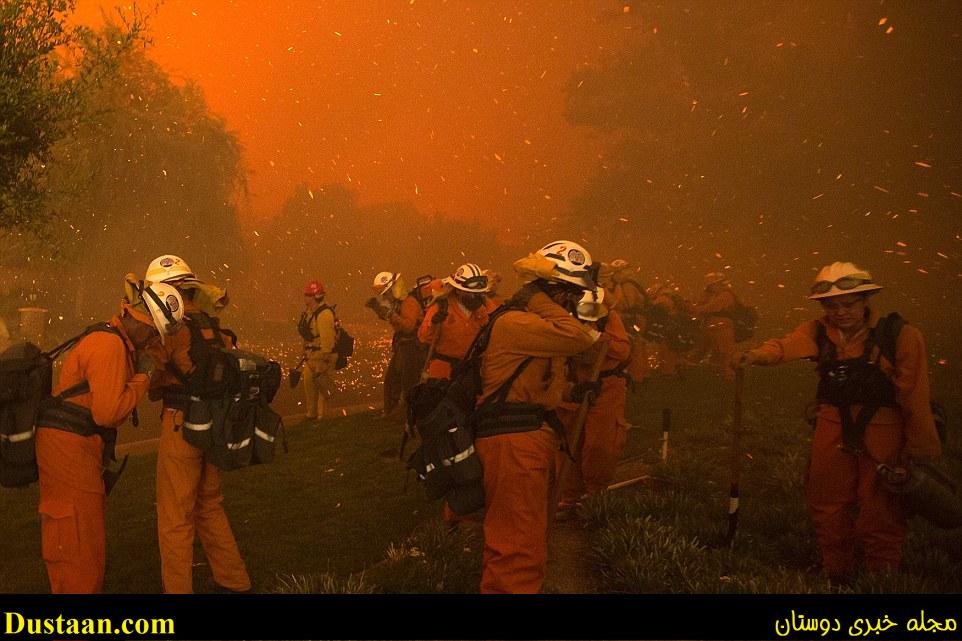 Inmate handcrew firefighters shield themselves from embers and heavy smoke as flames close in on houses at the Sand Fire on Saturday