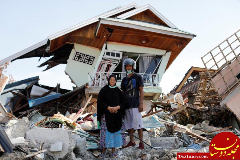 یک خواهر و برادر اندونزیایی در کنار خانه شان در جزیره سولاوسی ایستاده‌اند که در اثر زلزله تخریب شده است
