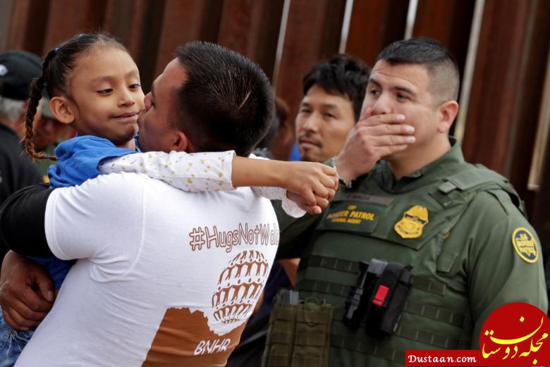 یک مرد کودکی را در مرز مکزیک و آمریکا در آغوش گرفته است