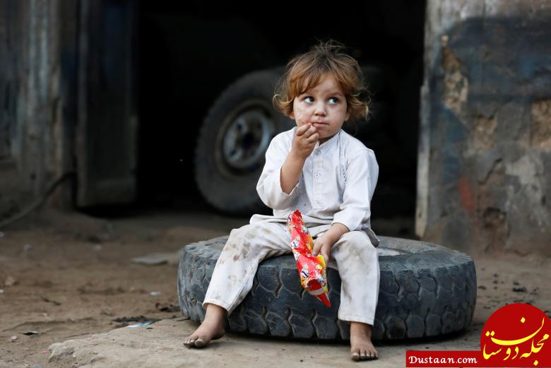 یک کودک برروی لاستیک در کارگاهی در شهر کراچی پاکستان نشسته و از غذای محلی می خورد